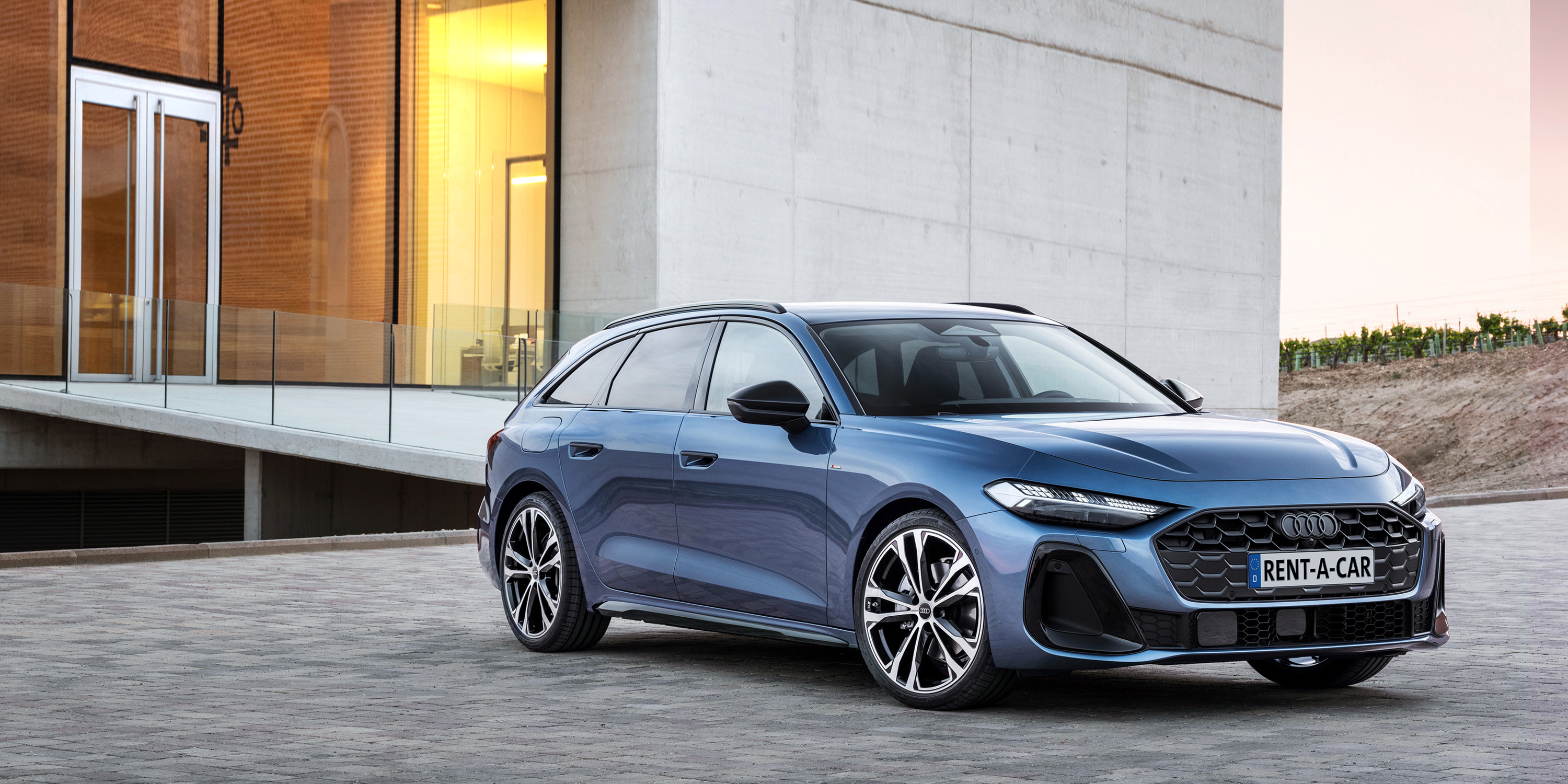 Blauer Audi A5 Avant steht seitlich vor futuristischem Gebäude